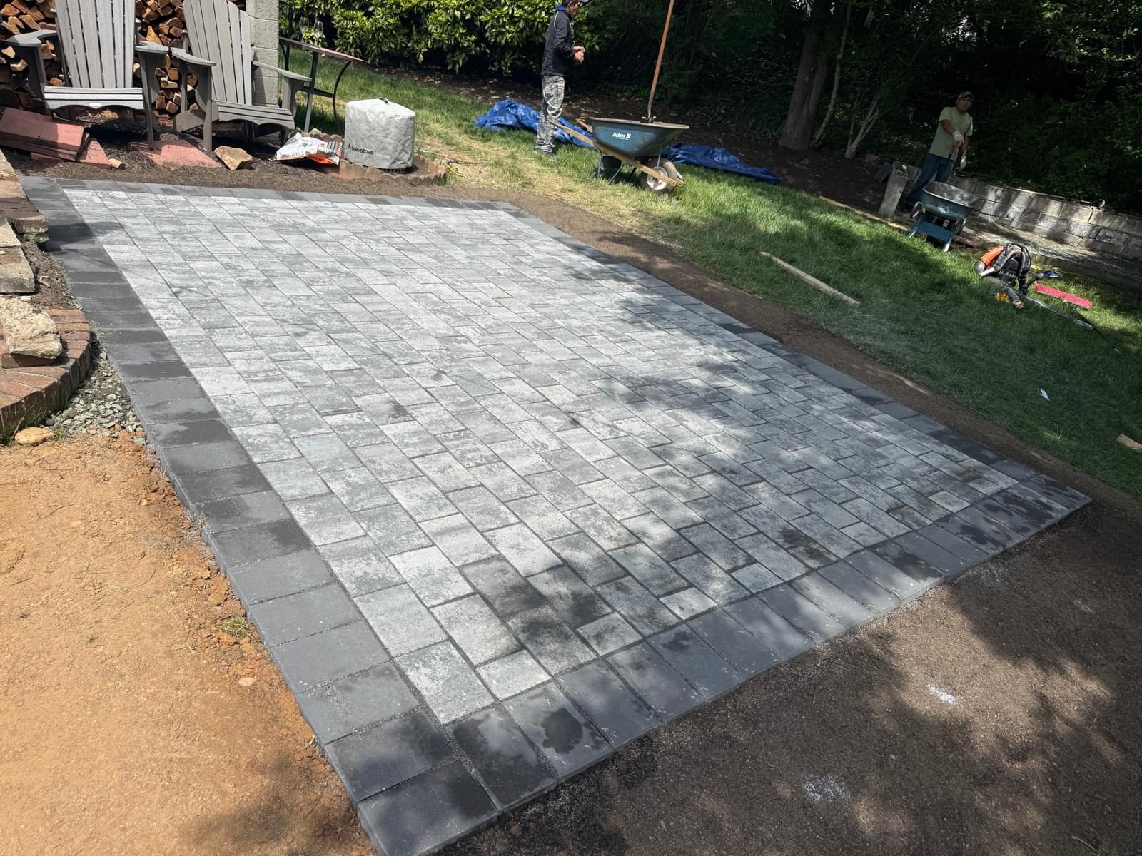 Large gray paver patio freshly installed in a backyard