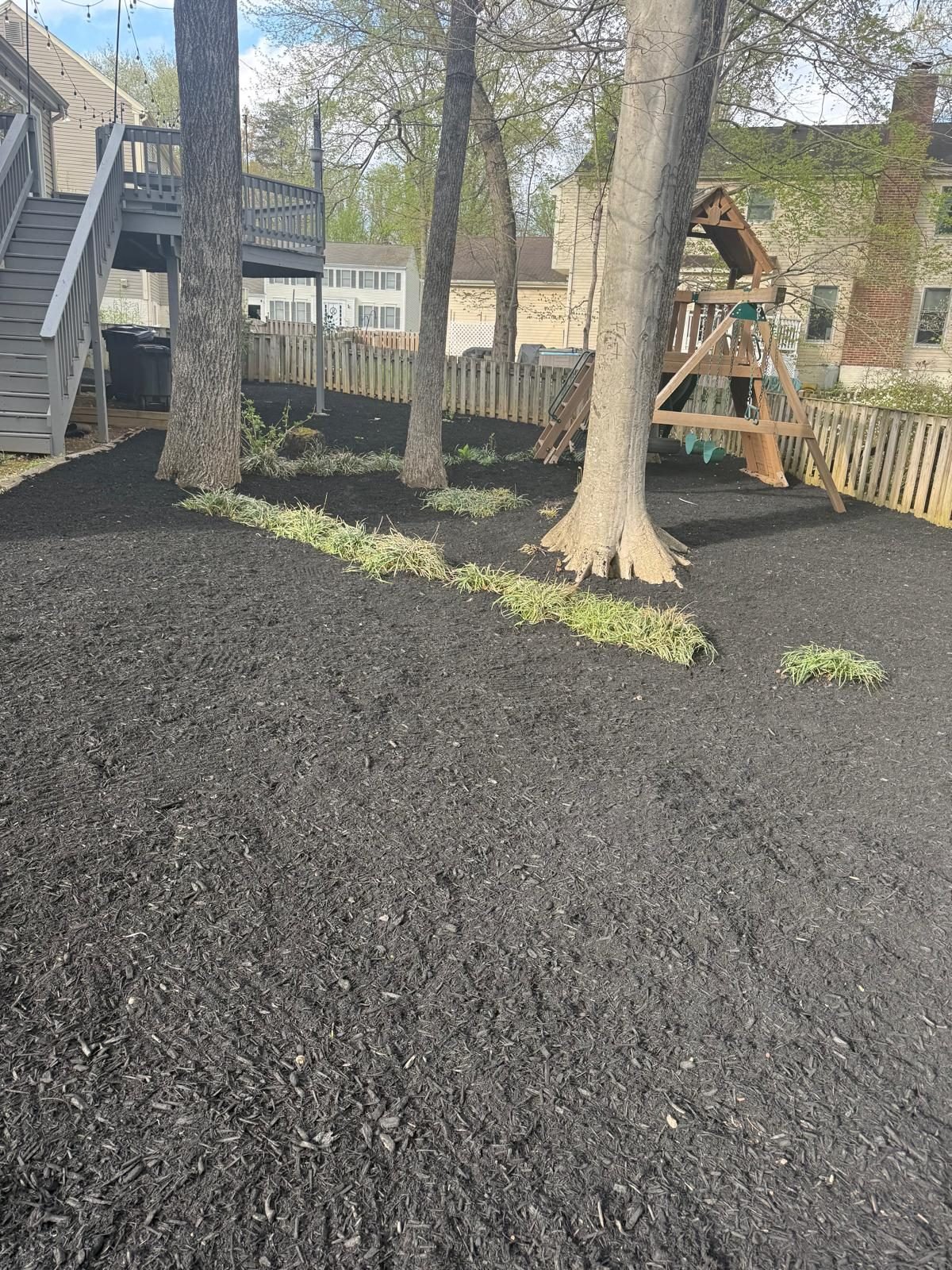 Fresh mulch beds around trees near a backyard play area