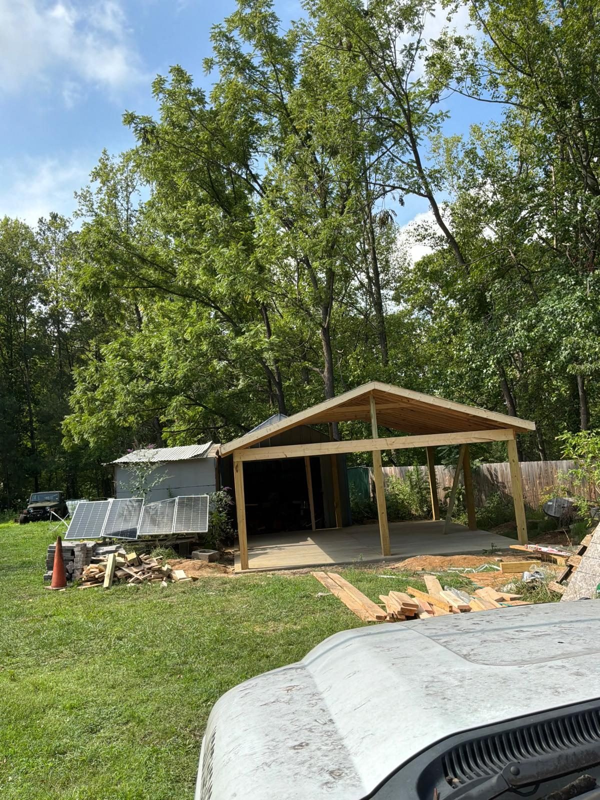 Completed wood pavilion with a solar panel setup nearby