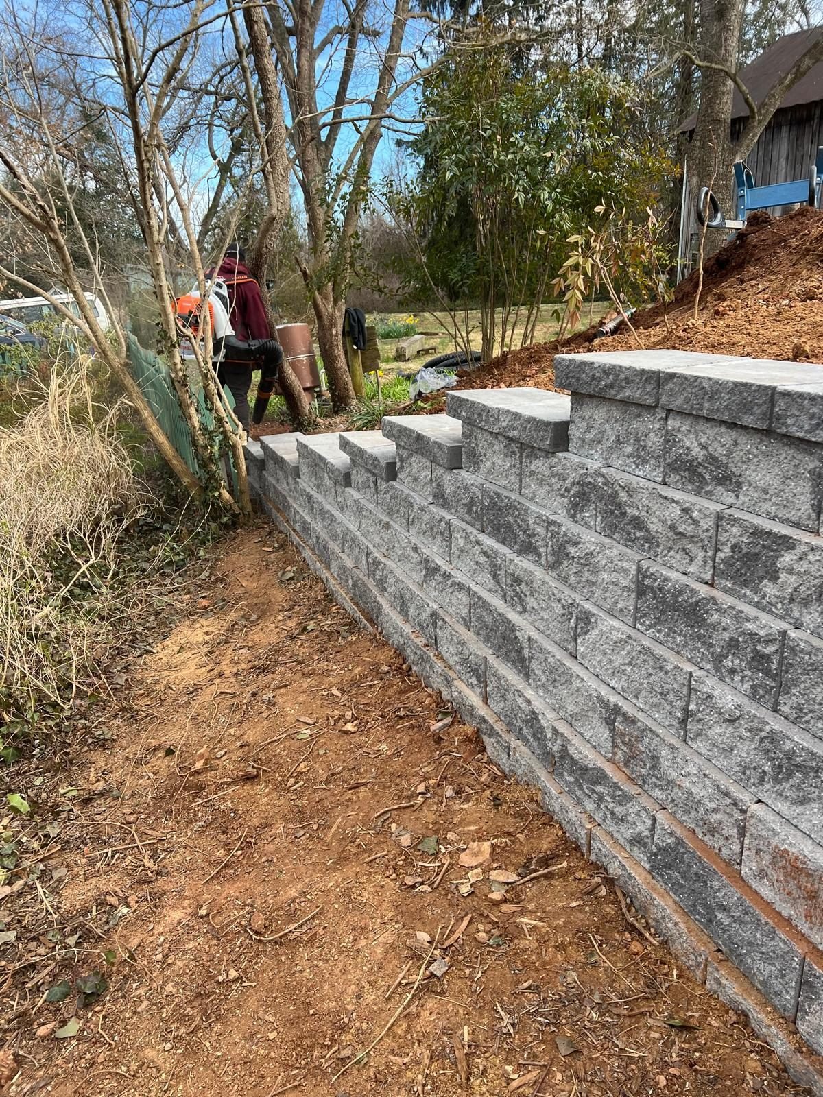 Crew building a block retaining wall staircase on a hillside