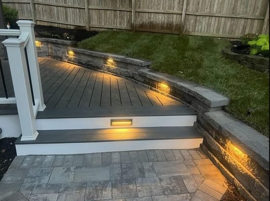Deck steps, stone wall and landscape lighting at night