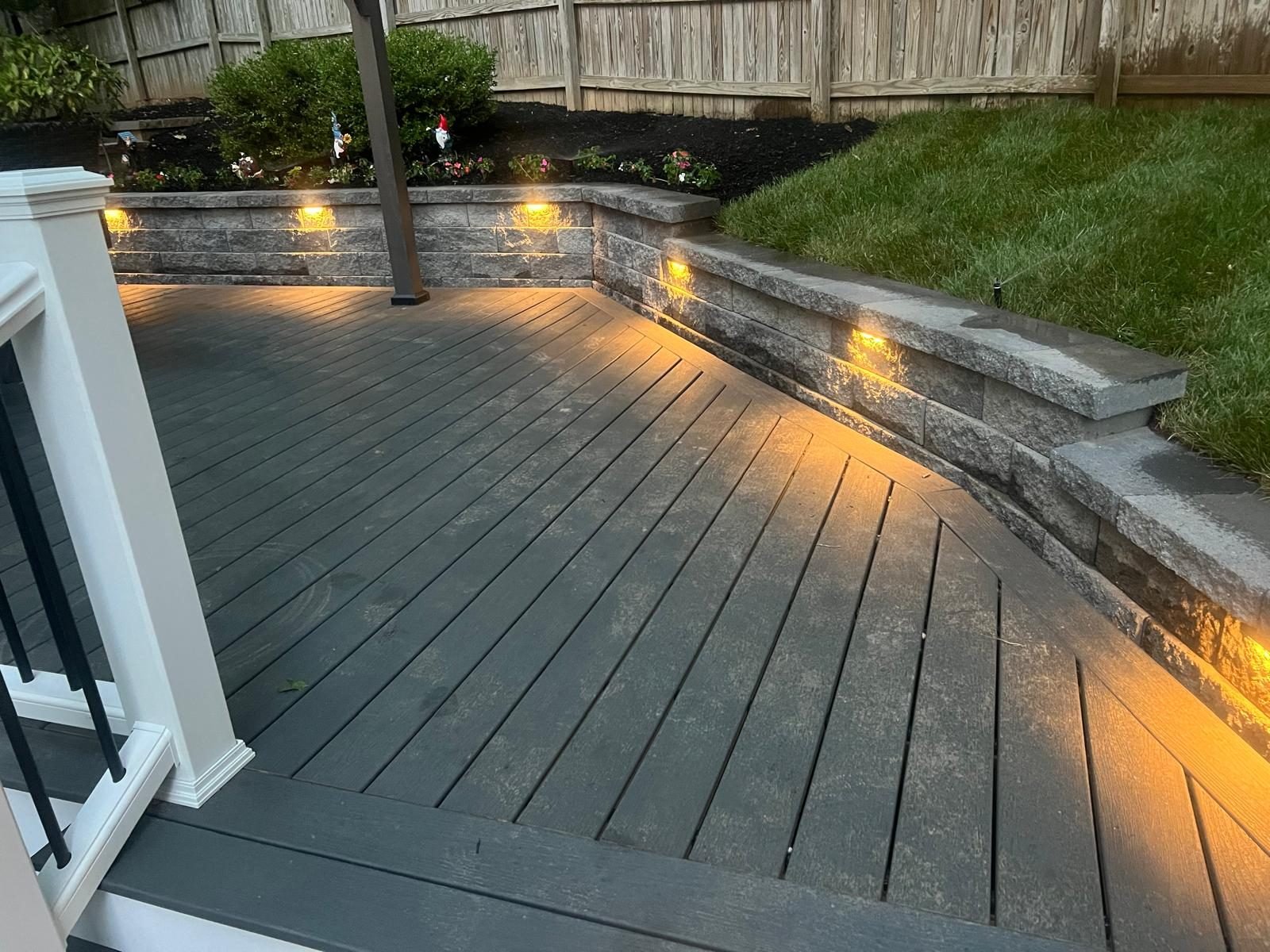 Deck steps, stone retaining wall and landscape lighting at dusk
